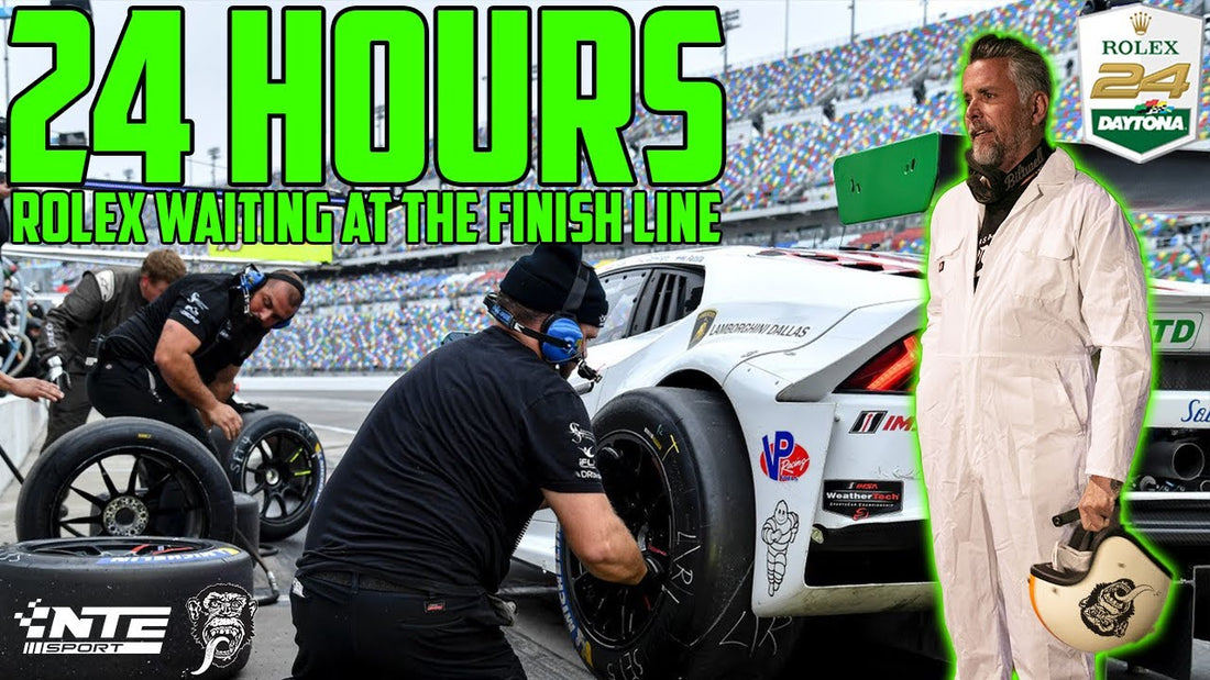 Pit crew changes a race car tire as a man in white racing gear stands beside it; 24 Hours Rolex Waiting at the Finish Line