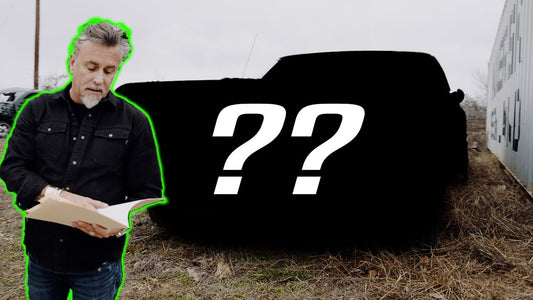Richard Rawlings holds papers beside a mystery muscle car silhouette with question marks outside a building