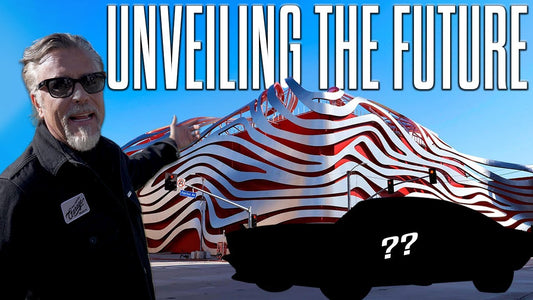 Richard Rawlings gestures toward a covered car outside the Petersen Automotive Museum with Unveiling the Future text