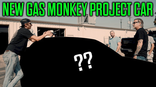 Several people gather around a blacked out car outside a garage with NEW GAS MONKEY PROJECT CAR headline
