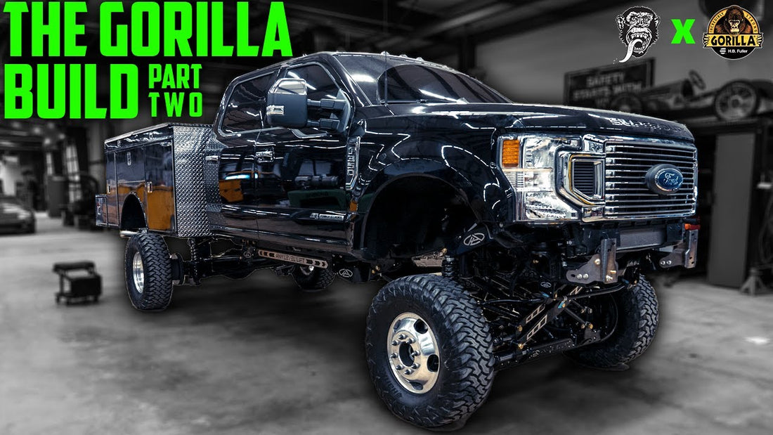 Front three-quarter view of a black utility truck showcasing lifted suspension in a garage, with The Gorilla Build Part Two