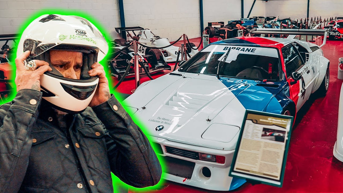 Man adjusts a white racing helmet beside a white, blue, and red race car in a motorsport museum