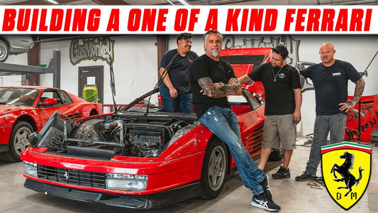 Four men pose beside a red Ferrari Testarossa with its front compartment open in a custom car garage