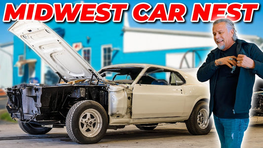 Man stands beside a classic Mustang with its hood open in a garage