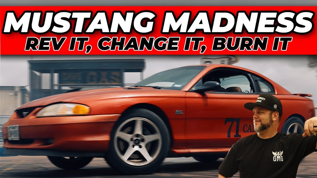 Orange Mustang driving past a man in a black shirt and cap on a paved surface