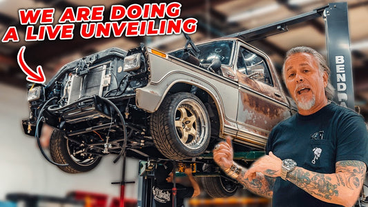 A man presents a patina 1979 Ford F100 on a lift during a live unveiling