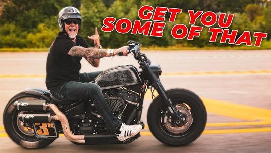 Biker rides a black motorcycle on a road with Get You Some of That overlaid