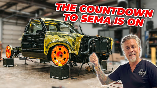 Man presents a partially assembled black and yellow pickup truck in a workshop; The countdown to SEMA is on