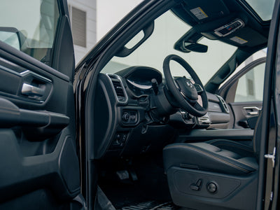 Open driver’s-side view of the Fox Factory Ram showcasing black leather interior with gold stitching and dashboard