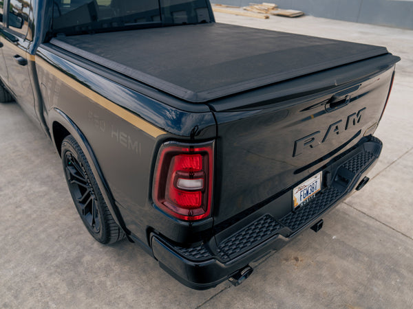 Rear three-quarter view of the Fox Factory Ram showcasing its metallic black finish, gold stripe, and covered bed